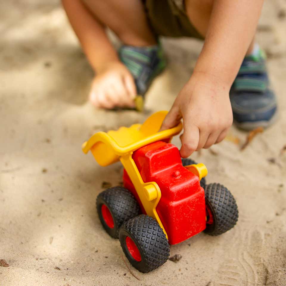 Kita Bärenhöhle: Kind spielt mit Fahrzeug im Sand