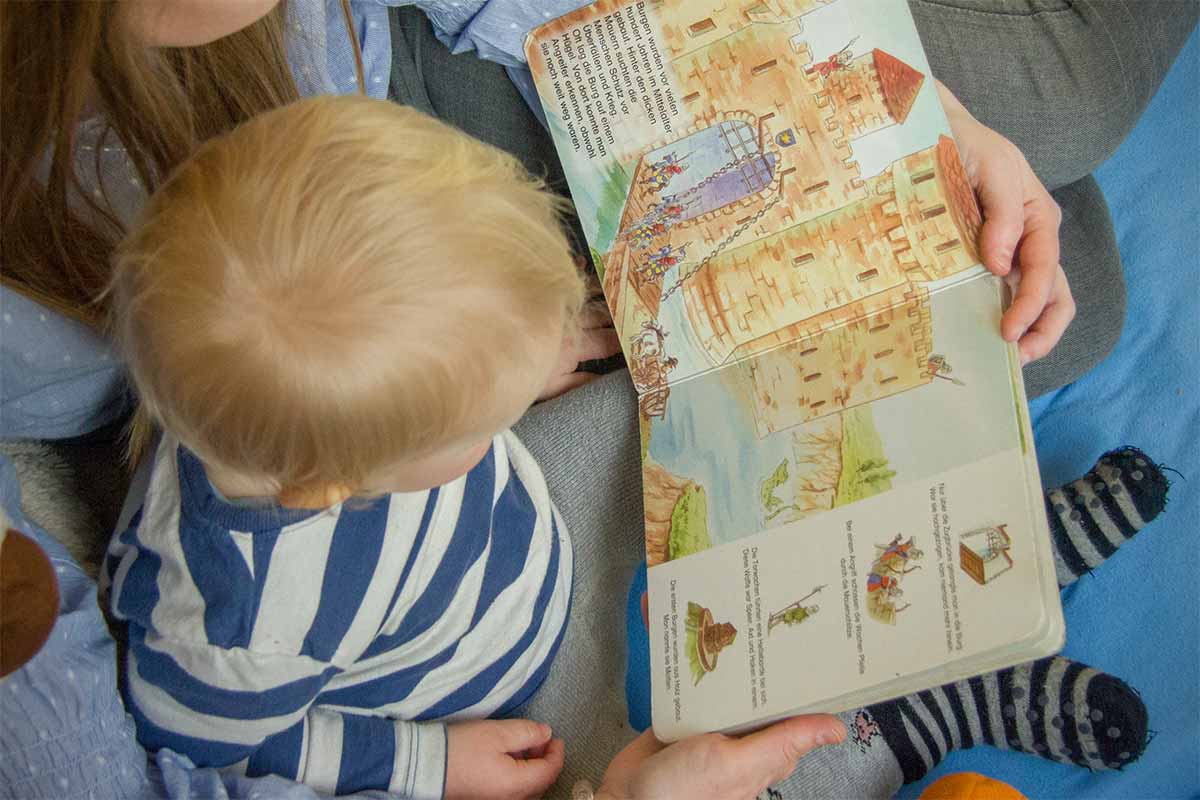 Kita Bärenhöhle: Praktikantin liest mit Kind ein Buch
